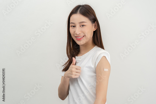 Portrait of pretty, beautiful asian young, teenage attractive after getting, receive anti virus vaccine covid-19. Showing arm on white bandage isolated on white background, copy space.
