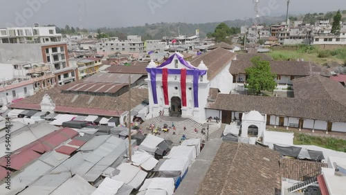 Aerial footage that is moving towards the Iglesia de Santo Tomás in Chichicastenango, Guatemala with Easter colors covering the facade. photo