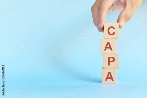 CAPA or corrective and preventive action on wooden blocks in blue background. photo