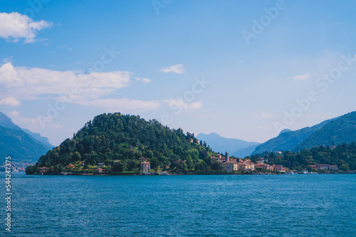 Beautiful panoramic view of Lake Como with fishing villages and the green Swiss Alps in the background on a sunny summer day. Lombardy, Italy.