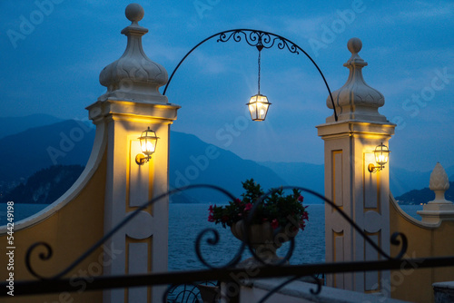Beautiful outdoor lanterns illuminating the deck overlooking Lake Como and the Swiss Alps during the dusk in Varenna, Lombardy, Italy.