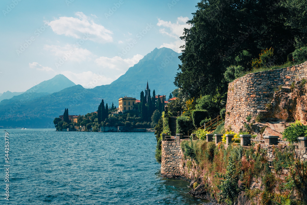 Wide panoramic view of Lake Como and the walking path along Villa Monastero's gorgeous lakefront garden in Varenna, Province of Lecco, Italy.