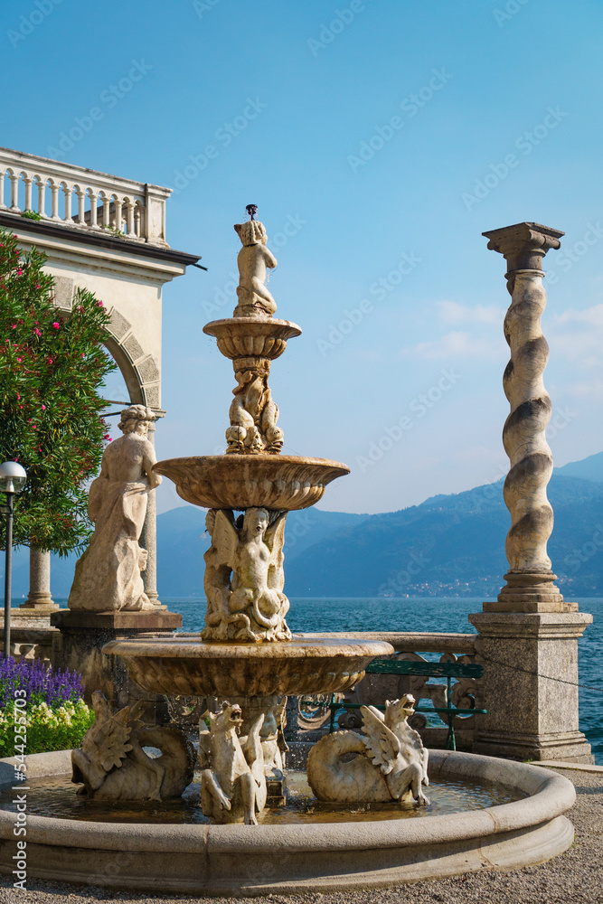 Stunning view of the fountain and Lake Como in front of the famous historic Villa Monastero, the villa of lords, Varenna, Province of Lecco, Italy.