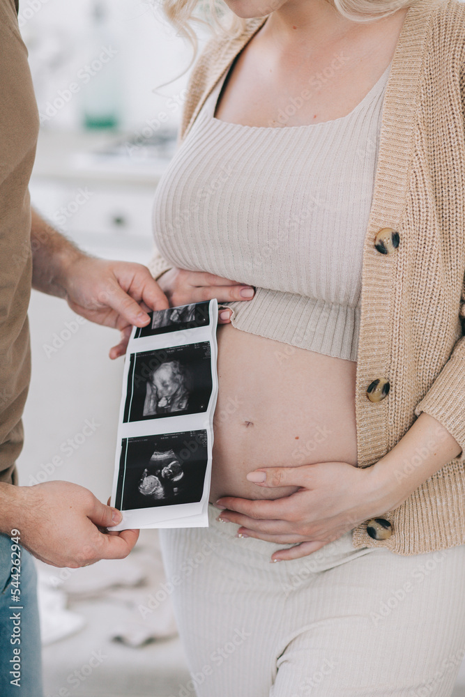 Pregnant woman's belly close-up and printed ultrasound screening. The concept of conscious fatherhood, happy motherhood and easy pregnancy. Pregnant woman's belly close-up and printed ultrasound screening. The concept of conscious fatherhood, happy motherhood and easy pregnancy.