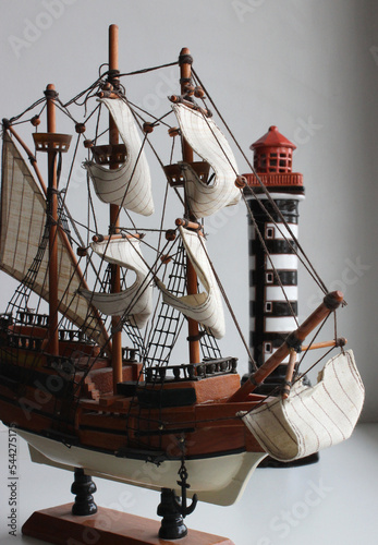 Miniature Of Wooden Sail Vessel On A Model Stand With Lighthouse Isolated Stock Photo
 photo