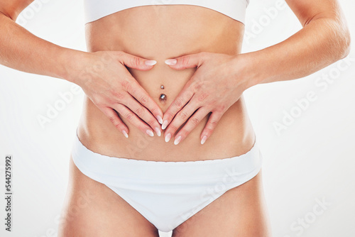 Woman, body and hands on stomach closeup for healthy digestion wellness or beauty lifestyle. Fitness person, healthcare support and hand on abdomen for cosmetic skincare in white background studio © Allistair F/peopleimages.com