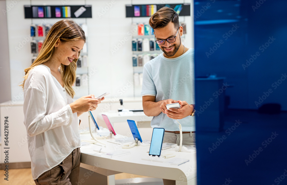 Tech shopping device gadget concept. Happy young people buying a new smartphone in mobile shop.