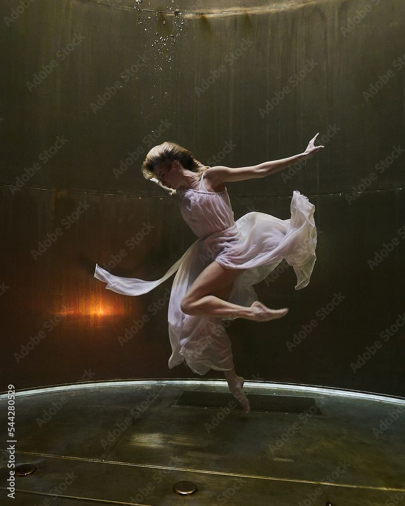 a ballerina dances underwater in a white flowing dress on a dark background in the depths fantasy world of adventure - obrazy, fototapety, plakaty 
