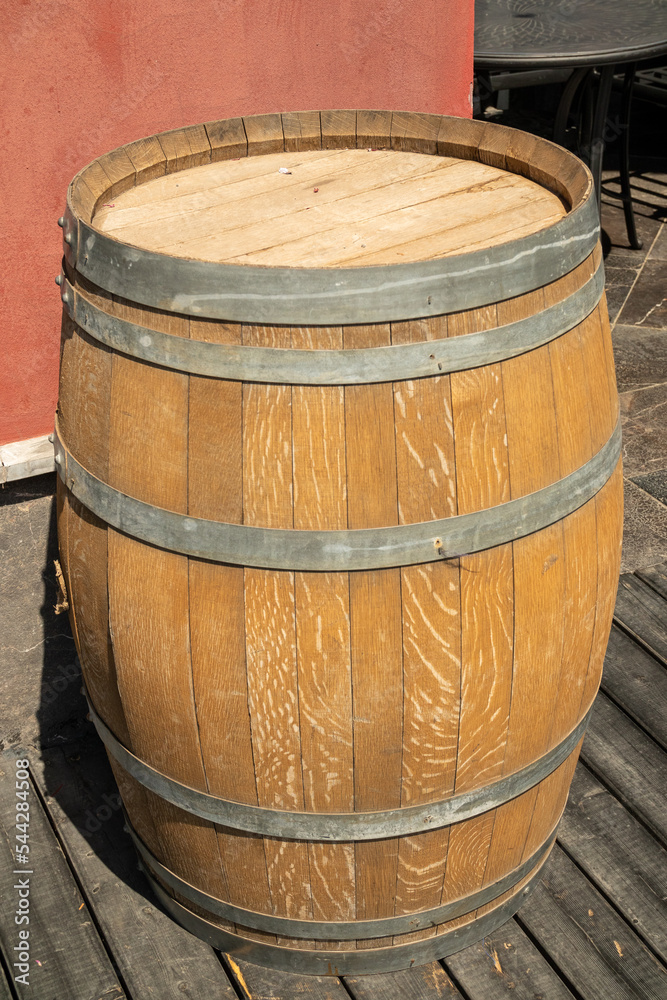 A large wooden barrel stands on the street near the building as a facade decoration. A large wooden barrel stands on the street near the building as a facade decoration.