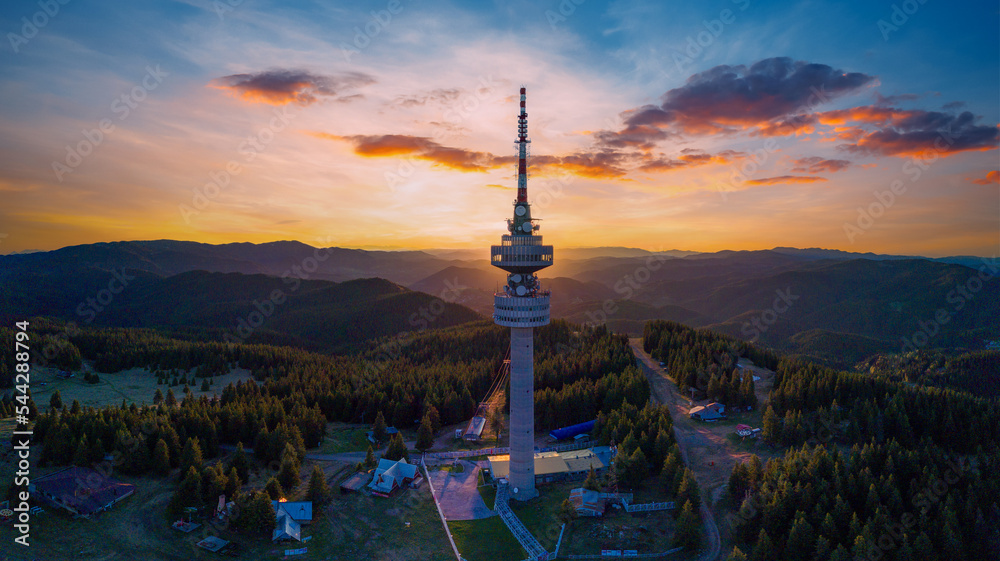 Tower Snezhanka in Rhodope mountains with fog, forest, sunbeams and sunny clouds. Panorama, top view