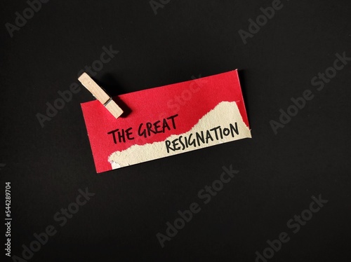 Red torn paper card clip with cloth pin on black copy space background with text written THE GREAT RESIGNATION, concept of the big quit, global trend ongoing when millions workers leave full time jobs photo