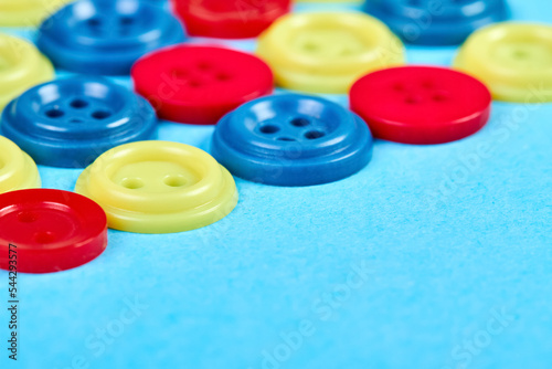 Multicolored buttons for clothess on a blue background. Close-up, selective focus