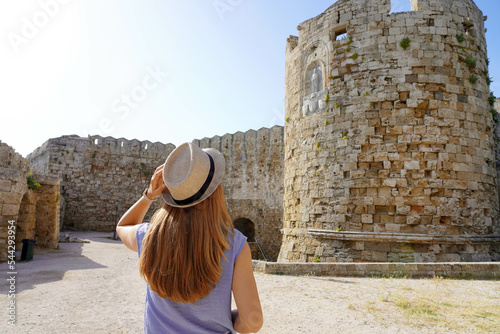 Holidays in Rhodes  Greece. Back view of traveler girl visiting Rhodes fortifications. Young female tourist visiting southern Europe.