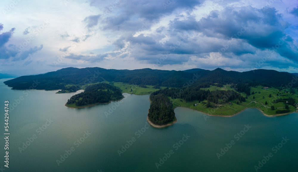 Lake covered with vegetation against backdrop of Rhodope mountains and clouds. Panorama, top view