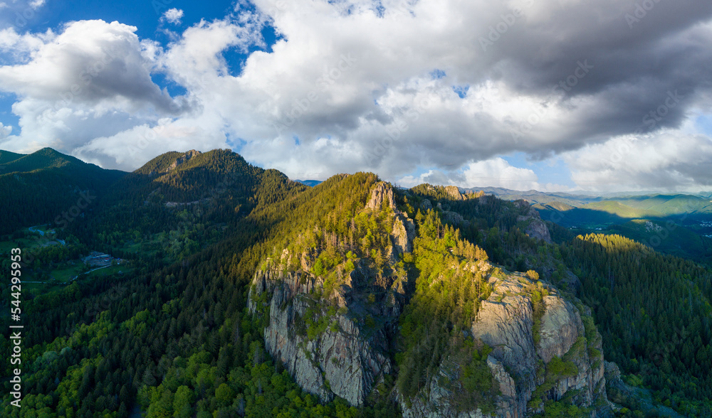 Peak of Rhodope mountain with forests against background of clouds. Panorama, top view