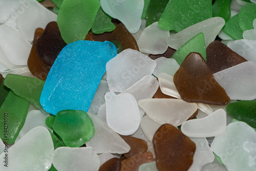 Beach litter - sea glass - worn pieces of broken bottle  - collected from the beach make a colourful display and an attractive wallpaper. A blue piece of sea glass makes an interesting contrast photo