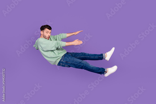 Full length photo of nice young guy flying away backwards confused trouble wear trendy gray outfit isolated on violet color background photo