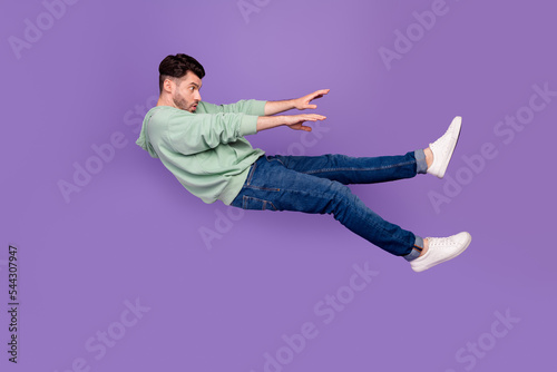 Full size photo of handsome young man flying away strong wind blow push dressed stylish khaki clothes isolated on purple color background