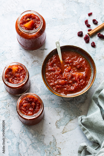 Bowl of tomato chutney with a few glass jars filled with the chutney next to it