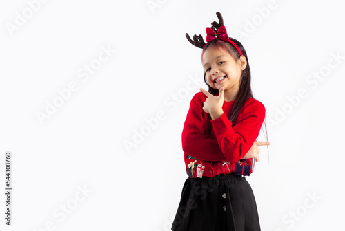 Little asian kid in red sweatshirt Christmas theme costume posing smiling and finger pointing on white background.