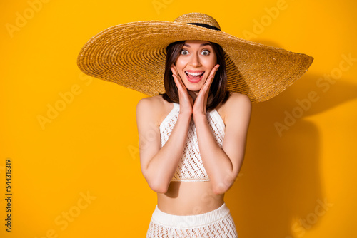 Photo of shocked excited girl dressed knitted bra straw cap arms cheeks smiling isolated yellow color background