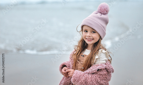 Photography Happy girl child on beach, portrait on winter holiday with pink beanie and kid smile on the Dublin seaside