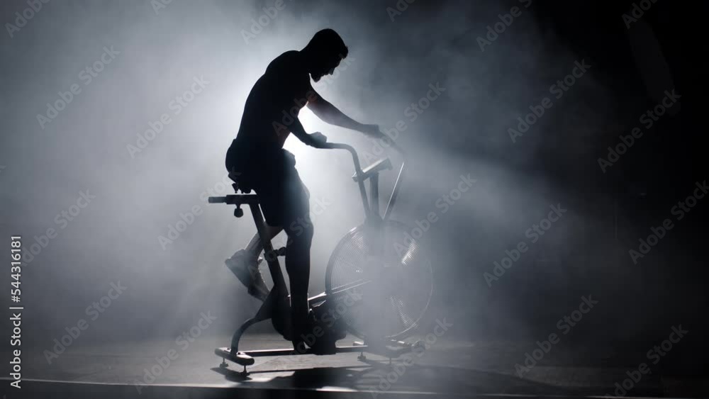 Sportive Athletic Male Has Fast Training on Stationary Bike .