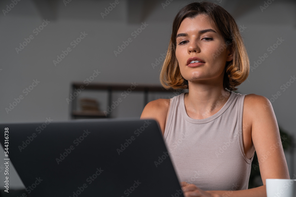 Thoughtful businesswoman in casual wear typing on laptop touching chin