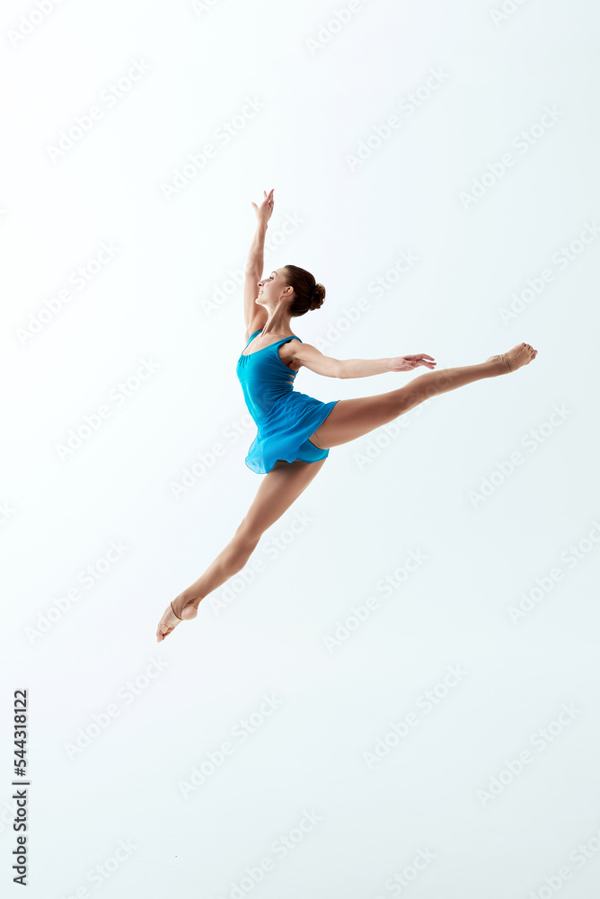 Beautiful young girl doing a ballet jump Sissone and wearing a blue tutu. Happy dancer isolated on white background. Jumping. Concept of art, sport, sportive life.