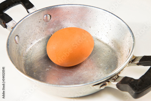 Old aluminum pan seen from above with an egg in the middle photo