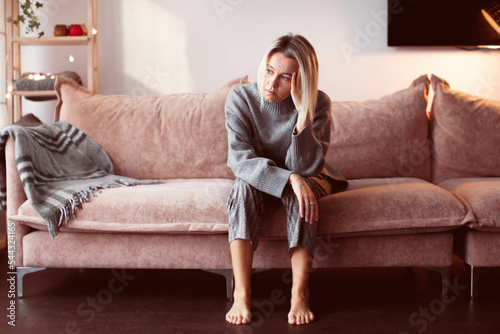 Depressed lonely unhappy mental woman sitting alone on the sofa feel stress