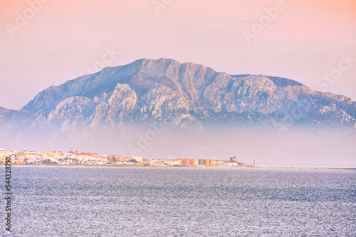 musa mountain in tarifa sea with fog and sunrise colors calm sea beautiful landscape photo