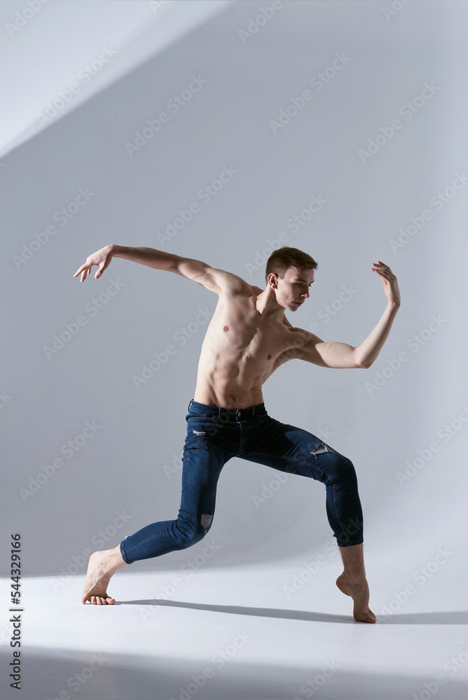 Handsome young man shirtless of modern ballet dancers in jeans. Concept of art, sport, fashion. Expressions. Isolated in white and grey background.