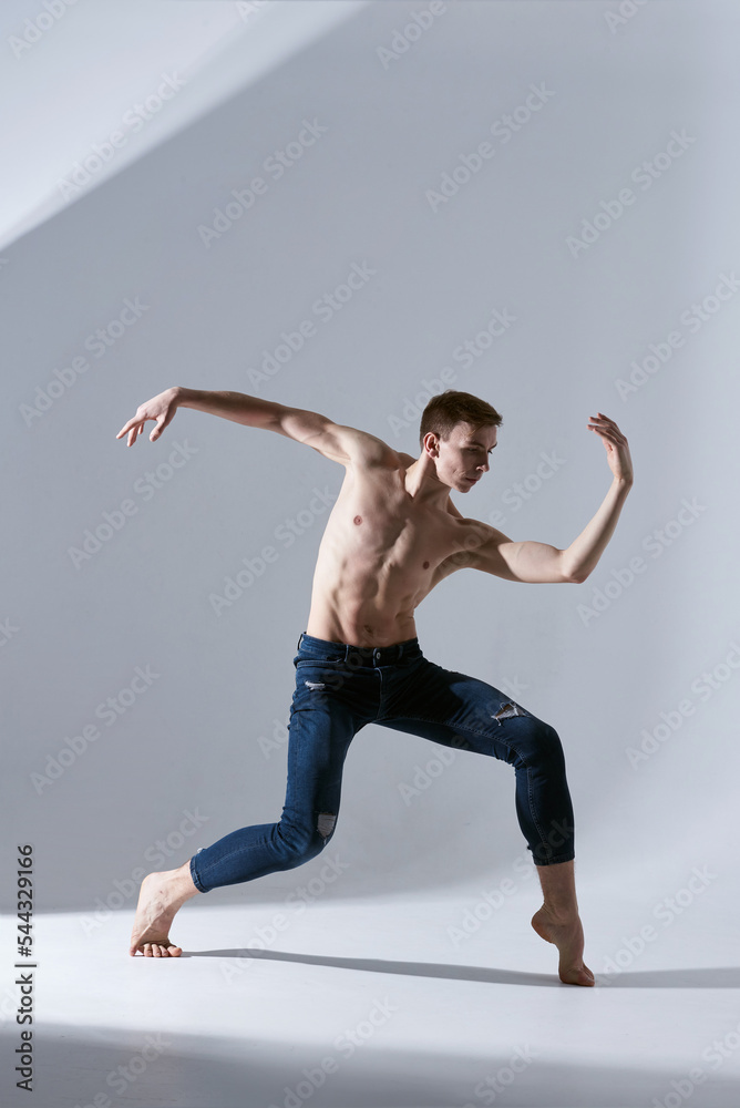 Handsome young man shirtless of modern ballet dancers in jeans. Concept of art, sport, fashion. Expressions. Isolated in white and grey background. Handsome young man shirtless of modern ballet dancers in jeans. Concept of art, sport, fashion. Expressions. Isolated in white and grey background.