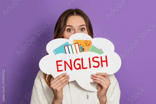 young shocked woman holding blank speech bubble with text learn english isolated on purple background photo