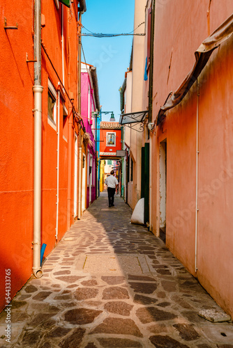 Colorful alley of Burano with tourist walking by
