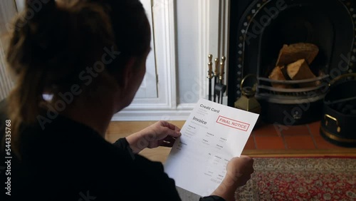 An unrecognizable female opening a debt letter. The woman is reading a credit card bill final notice at home photo