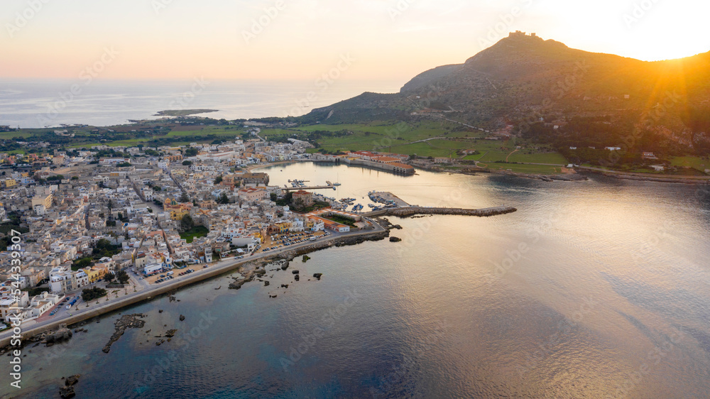 Aerial view at sunset on the island of Favignana. It's an Italian island belonging to the archipelago of the Aegadian islands, in Sicily, Italy. On foreground there is the little harbour.