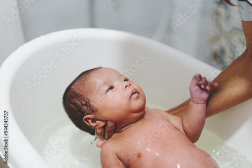 hands of mother holding small toddler girls in a bathroom indoors at home. mom, kid and healthcare concept