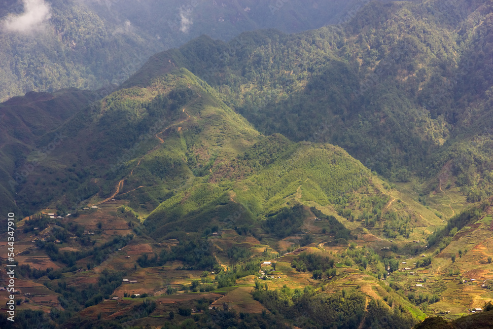 Green villages with terraced fields on the slopes of a hill around Sapa in North Vietnam.