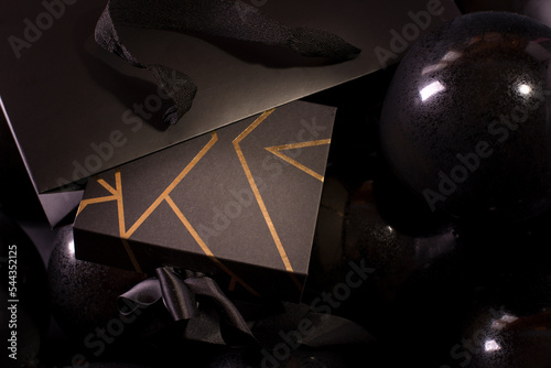 Black Friday Shopping Concept with Black color gift box decorated with Gold Stripes laying on Black baloons.