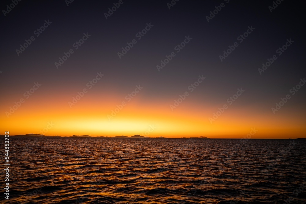 sunset over the ocean in golden light with waves and yachts
