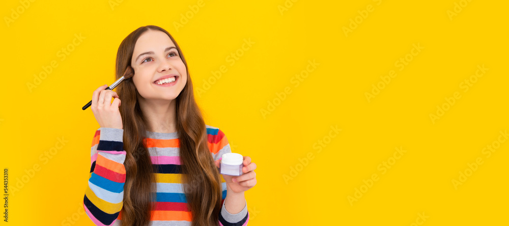 It takes makeup to look natural. Happy girl apply makeup. Child smile using foundation brush. Cosmetics for teenager child, poster design. Beauty kids makeup, banner with copy space. It takes makeup to look natural. Happy girl apply makeup. Child smile using foundation brush. Cosmetics for teenager child, poster design. Beauty kids makeup, banner with copy space.