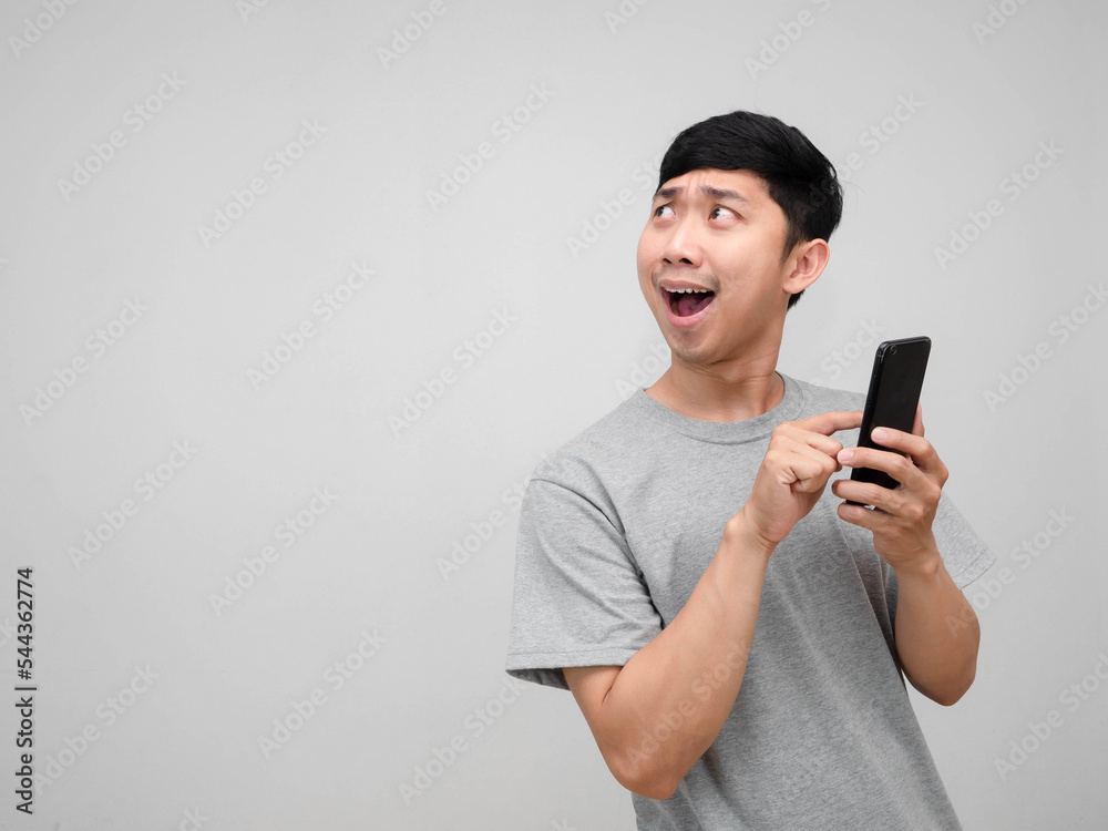 Man grey shirt feels excited using monile phone in hand gesture turn around to looking Man grey shirt feels excited using monile phone in hand gesture turn around to looking