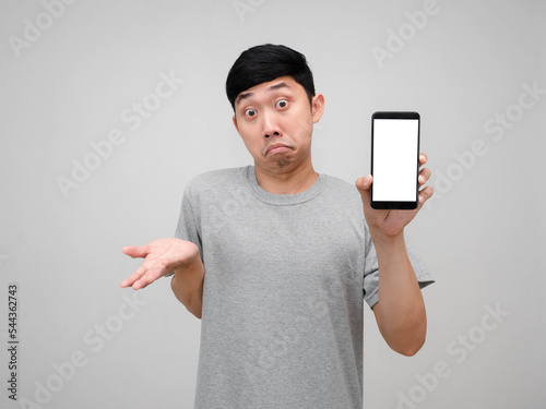 Young man grey shirt show cellphone white screen gesture doubt I don't know  isolated