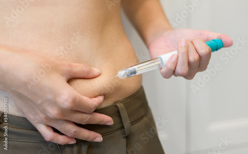 Close up woman using IVF treatment injection on belly to prepare reproductive fertility   Ovulation stimulation .