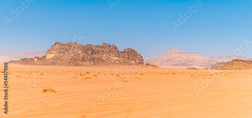 A panorama view of a sandy and rocky landscape in Wadi Rum, Jordan in summertime