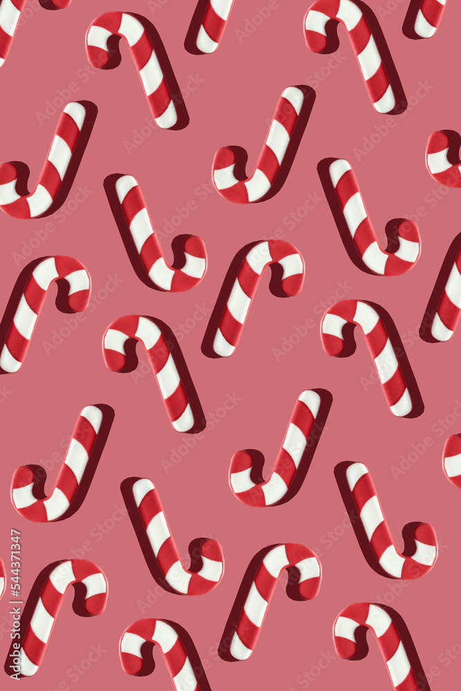 Red and white sugar candy cane sticks with sharp shadows on a pink background. Christmas party holiday seamless pattern. New year wallpaper design. Creative minimal greeting card. Red and white sugar candy cane sticks with sharp shadows on a pink background. Christmas party holiday seamless pattern. New year wallpaper design. Creative minimal greeting card.