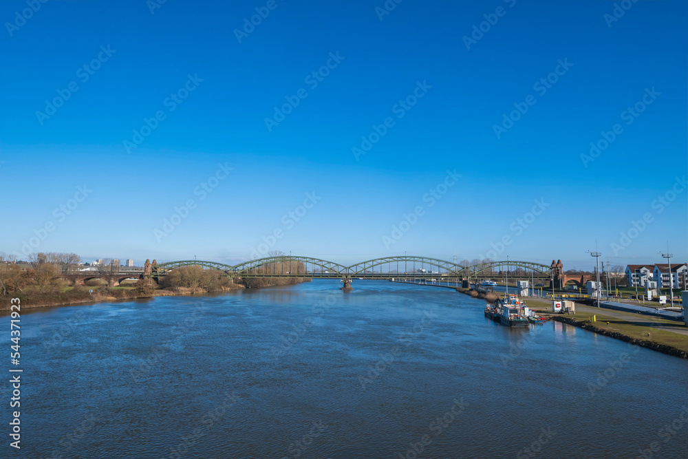 View from the barrage of the Main near Kostheim - Germany on the river with the old railway bridge in the background under a bright blue sky