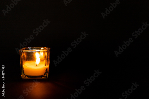 Candle in a glass beaker on a black background